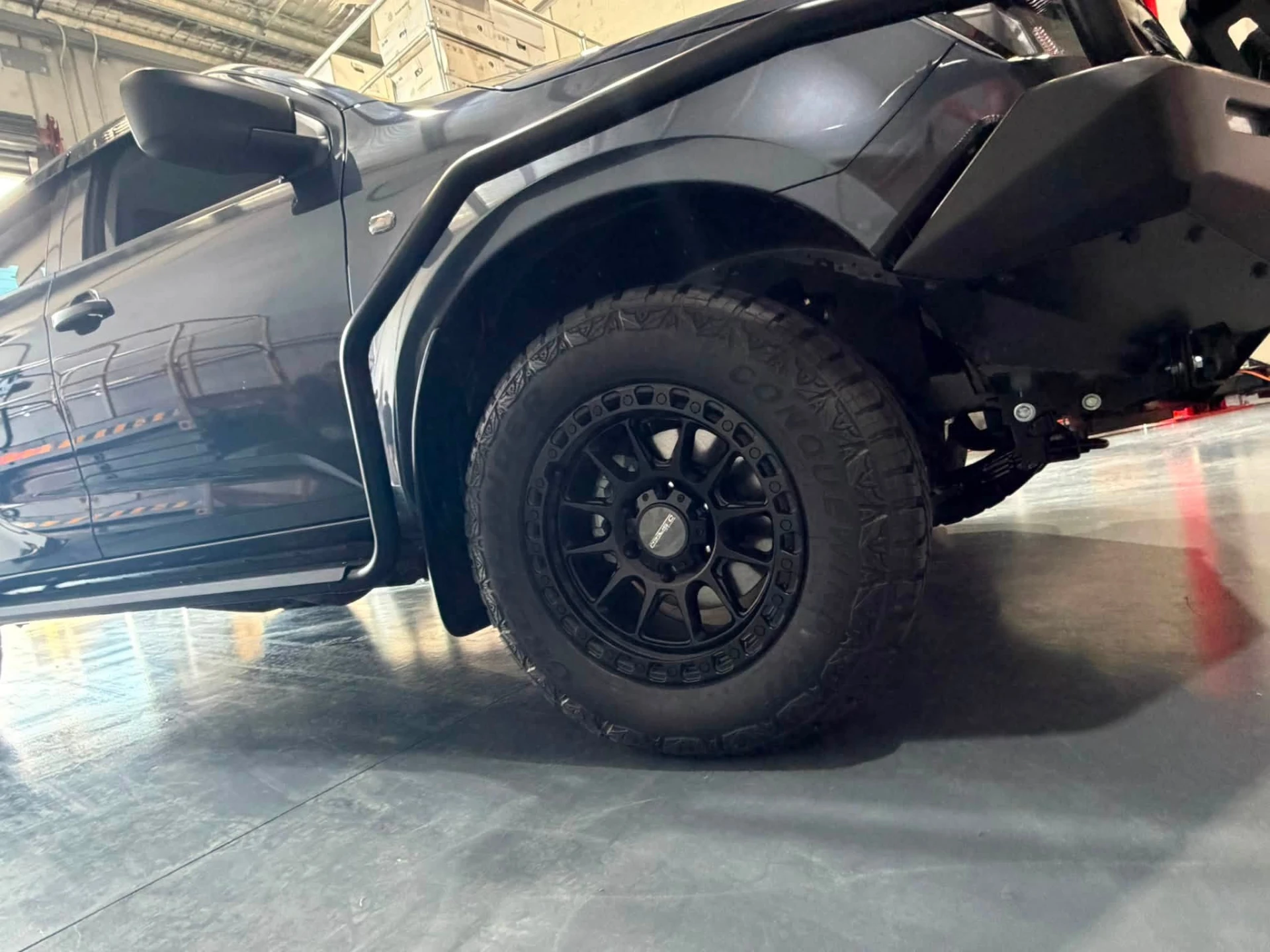 Black off-road alloy wheel and all-terrain tyre fitted to a 4x4 in the workshop at Australia's Most Wanted Wheels and Tyres Bathurst